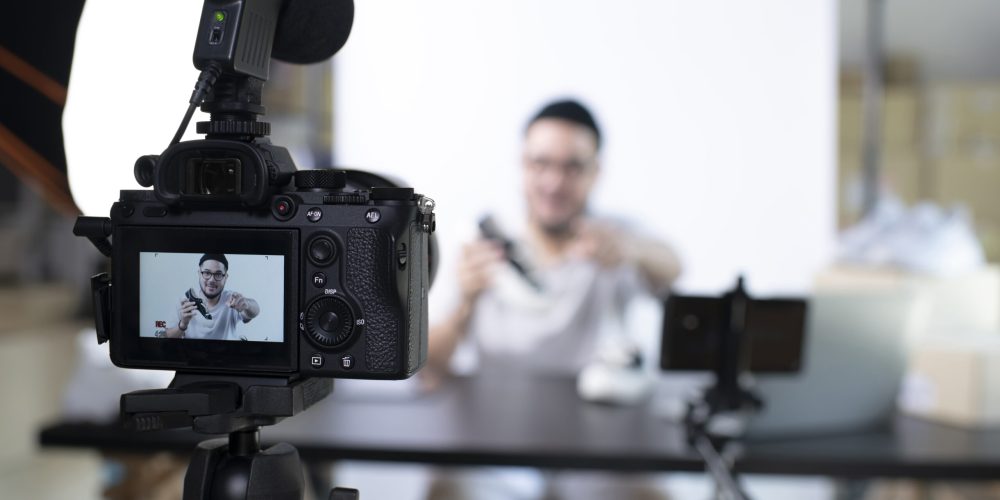 Young attractive Asian man blogger or vlogger looking at camera reviewing product. Modern businessman using social media for marketing. Business online influencer on social media concept.